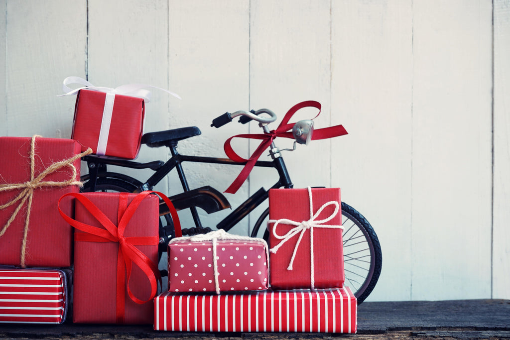 Bike against wall with Red bow and red wrapped gifts
